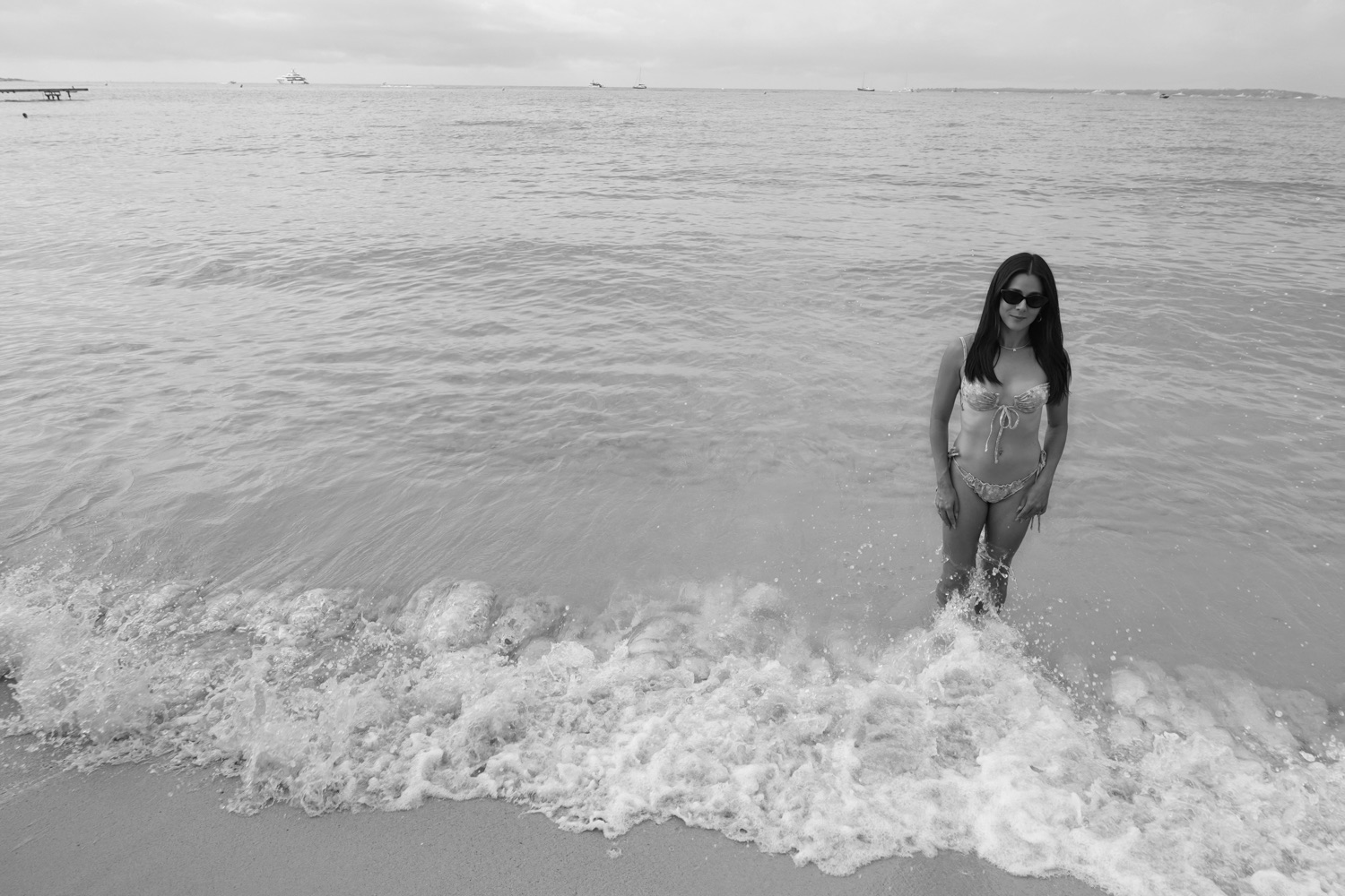 Anie standing in the surf at the beach, in black and white